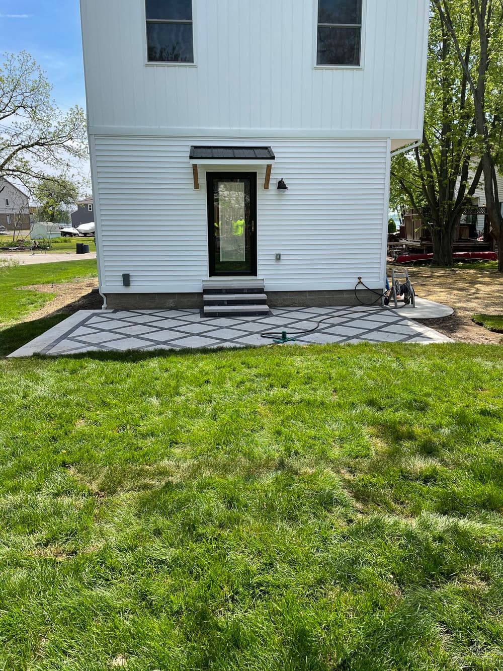 Modern home exterior featuring a patterned concrete patio and lush green lawn.