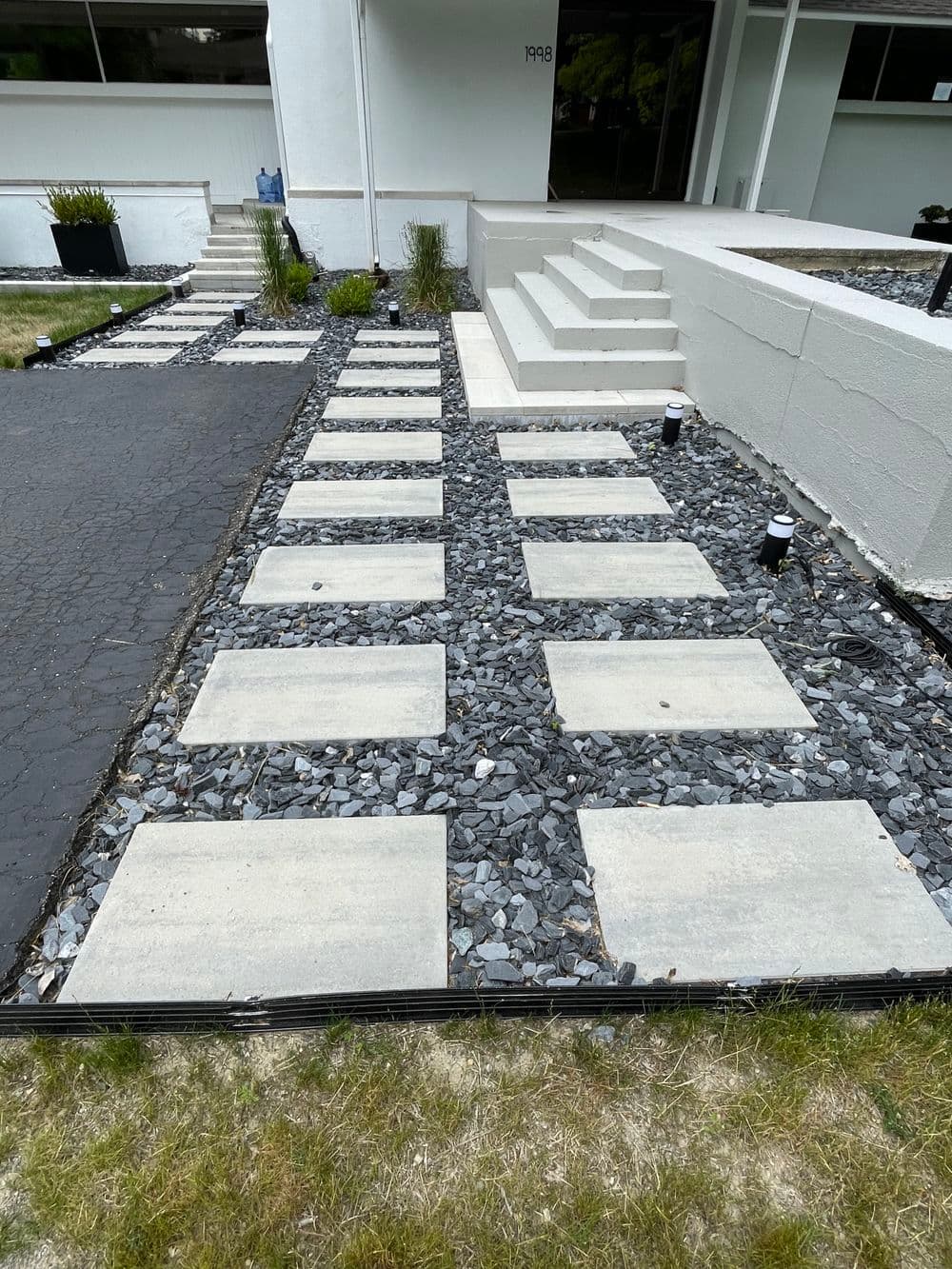 Modern concrete walkway with gravel accents leading to a contemporary building entrance.