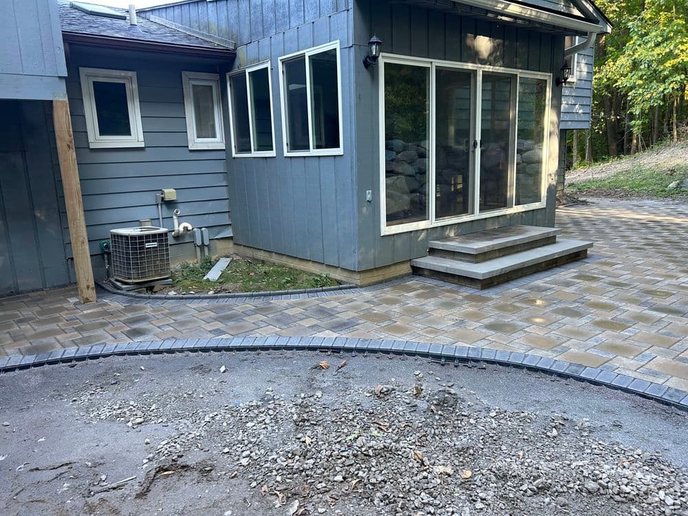Patio renovation with paved walkway, air conditioning unit, and house exterior.